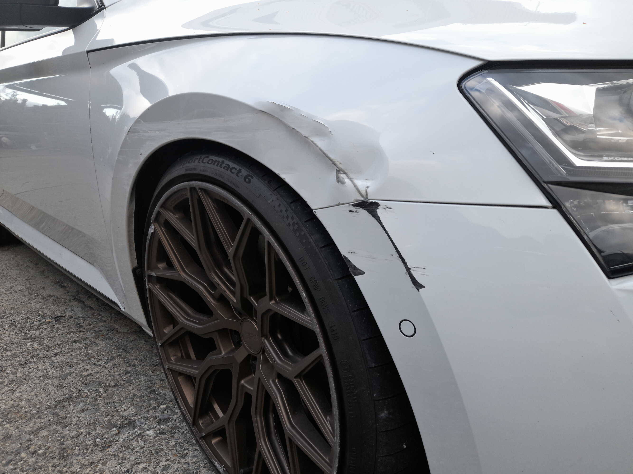 Auto in weiss mit Carrosserie- und Lackschaden an Kotflügel und Stossfänger.